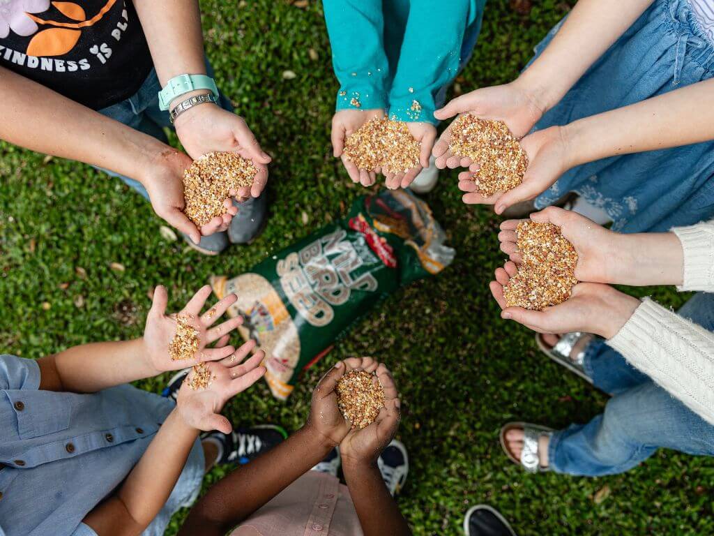 Group of children cupping hands full of Westerman’s wild bird seed outdoors