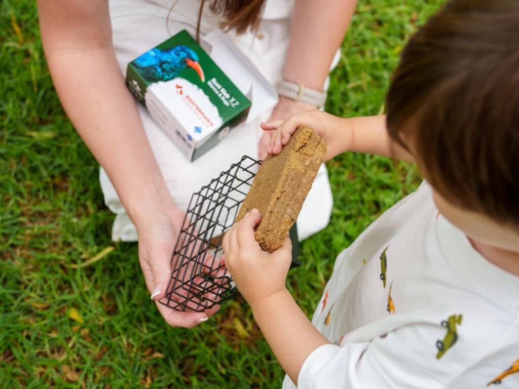 A child places a Westerman’s suet slab into a suet slab feeder while an adult holds the packaging.